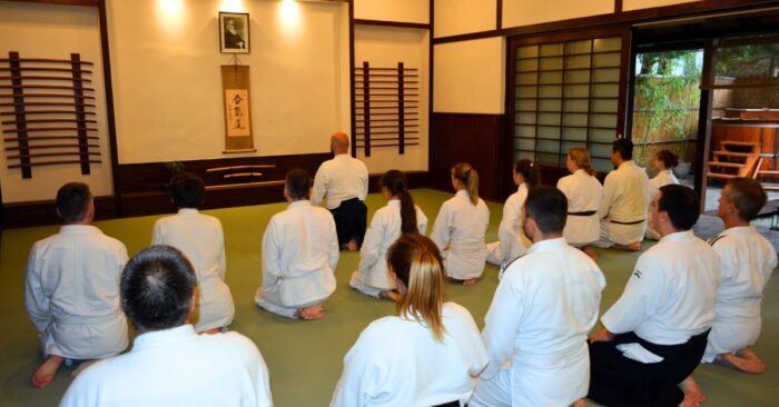 Aikido gyakorlók szejzában ülnek a dojoban, tiszteletadás közben a gyakorlás előtt