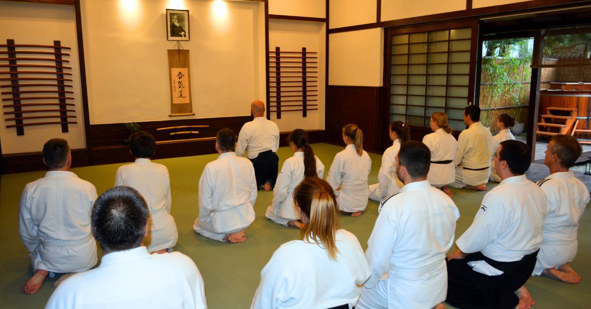 Aikido gyakorlók szejzában ülnek a dojoban, tiszteletadás közben a gyakorlás előtt